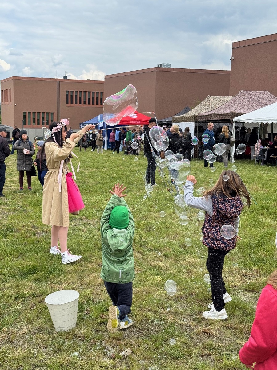 Dzieci bawią się na trawie puszczając bańki mydlane