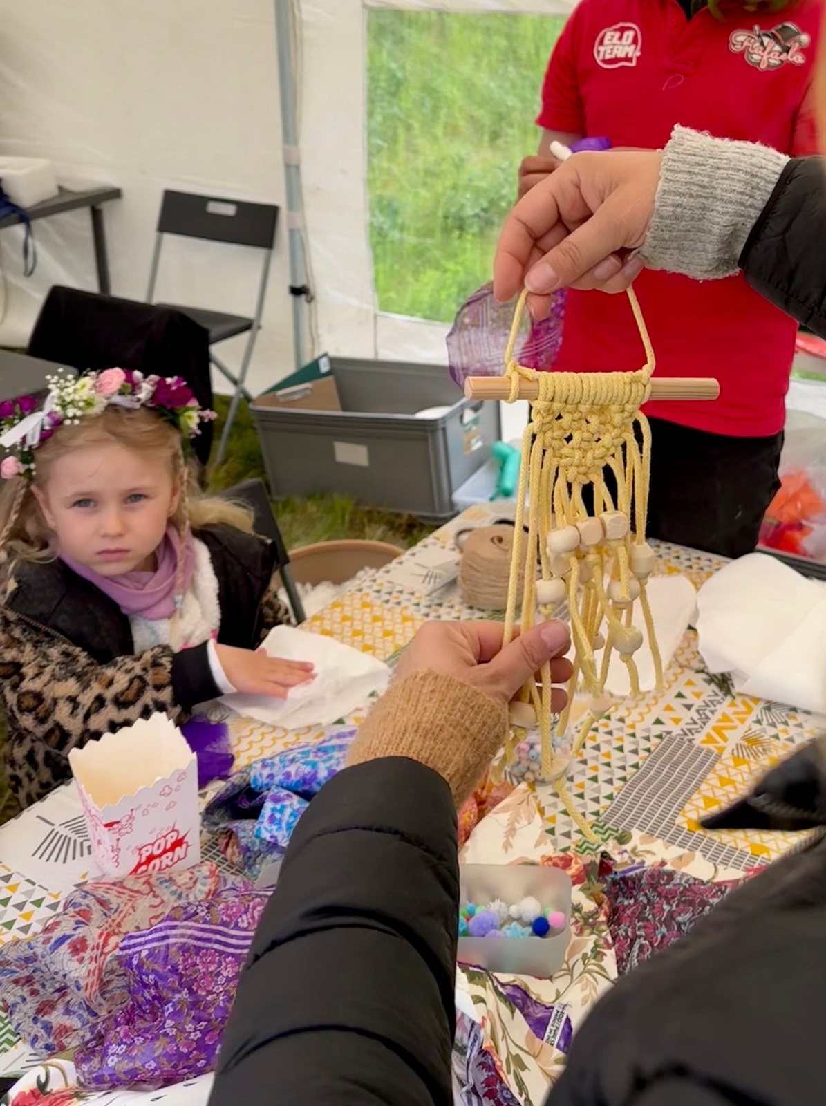 Dziewczynka siedzi przy stole i bierze udział w zabawach z wykorzystaniem włóczek i nici.