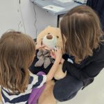 Kobieta i dziecko mierzą maskotkę - beżowego misia.