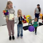 Dzieci w różnym wieku z kolorowymi wiatraczkami i balonikami.