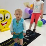 Chłopak i dziewczynka stoją na niedużej czarnej macie z podziałką pokazującą odległość.