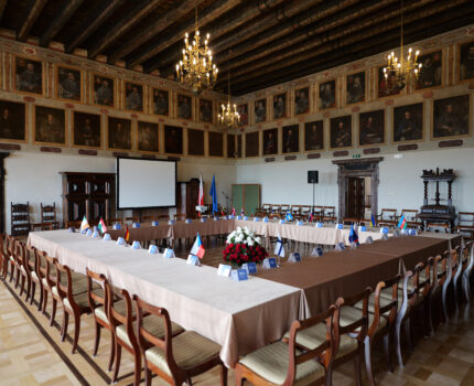 Duża, zabytkowa sala ze starymi portretami na ścianach, brązową drewnianą posadzką. Na sali ustawione w kształcie kwadratu stoły.