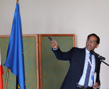 Mężczyzna w garniturze i w okularach podczas prezentacji.