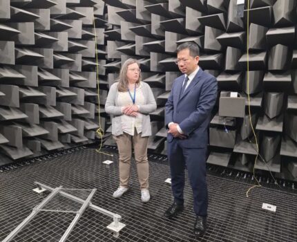 Kobieta i mężczyzna stoją w ciemnoszarym pomieszczeniu laboratoryjnym akustyki - w komorze bezechowej.