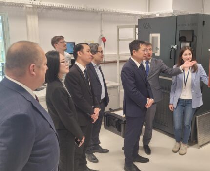 Grupa kilkorga ludzi zwiedza pomieszczenie laboratoryjne w Kampusie GUM.